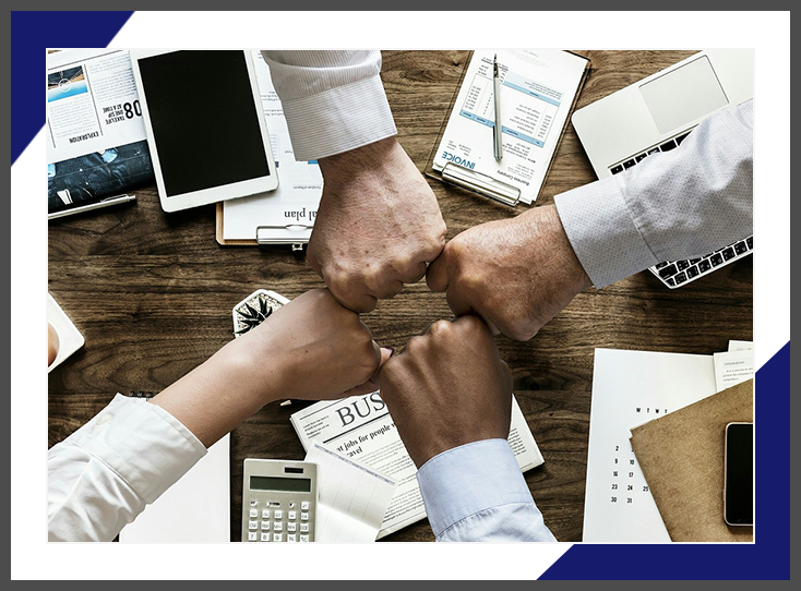 A group of people holding hands on top of a table.