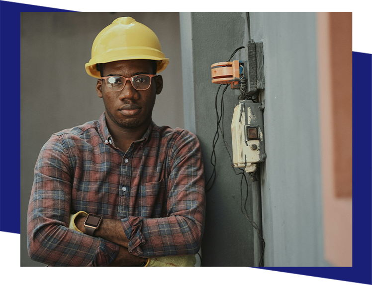 A man in a hard hat standing next to an electrical box.