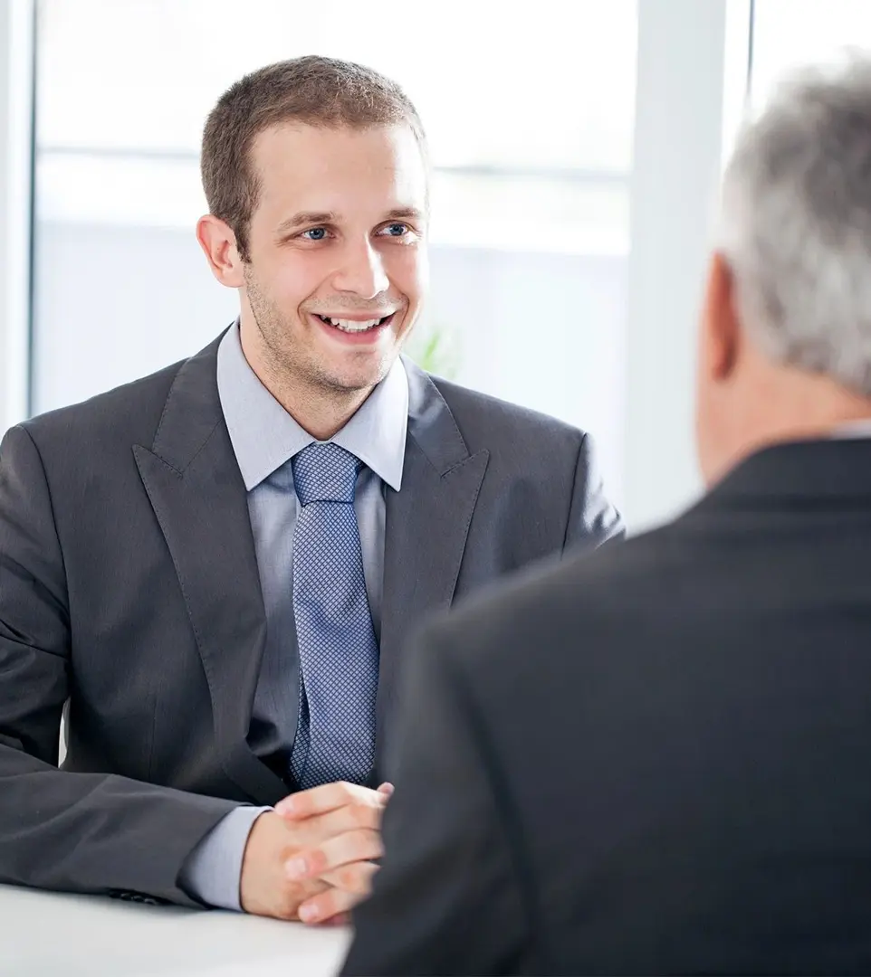 A man in suit shaking hands with another man.