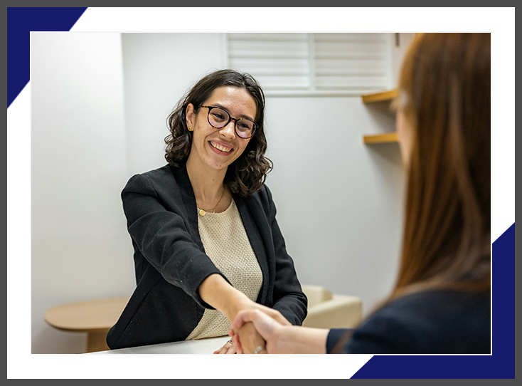 A woman shaking hands with another person in front of a mirror.