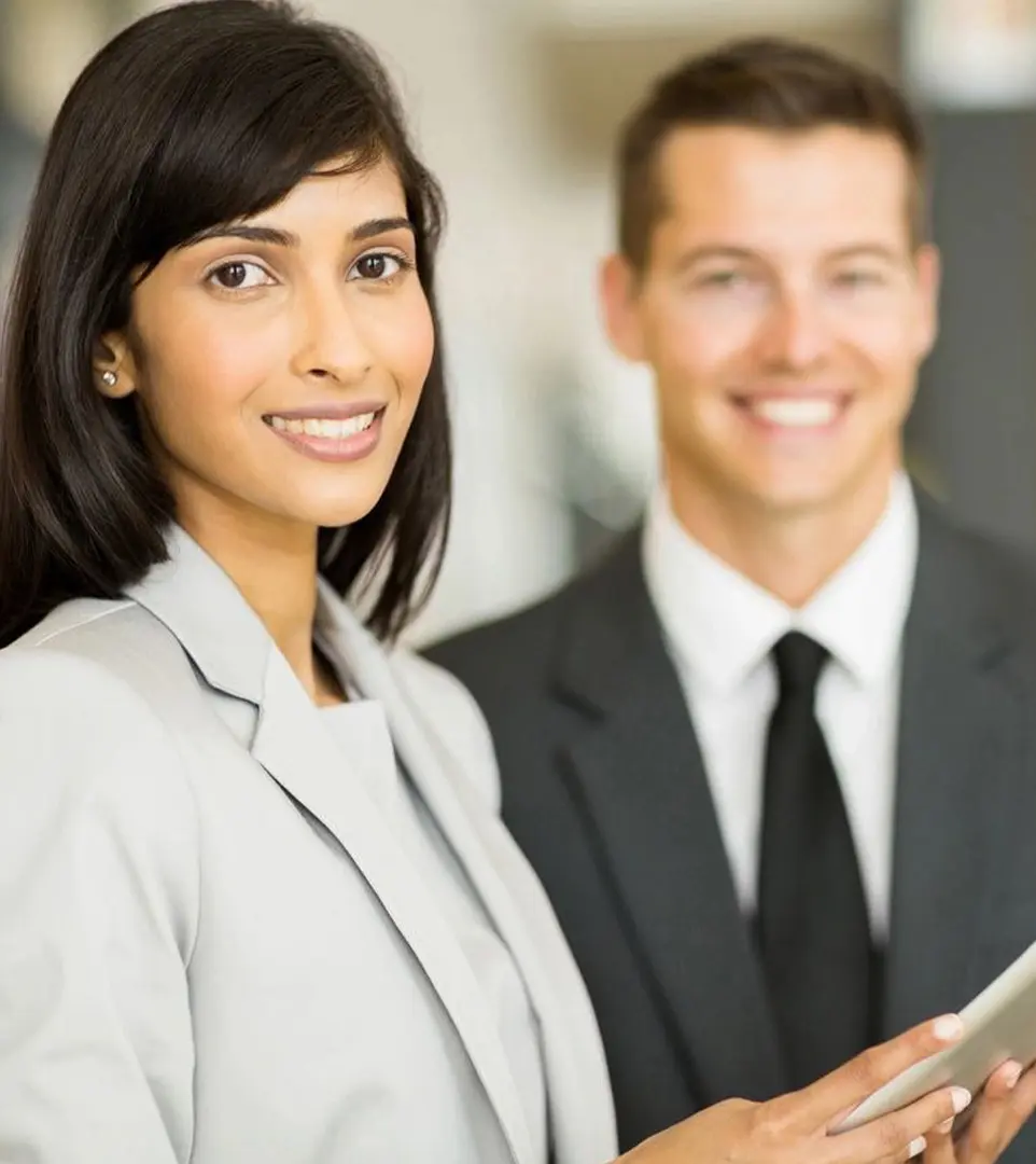 A woman and man in business attire smiling for the camera.