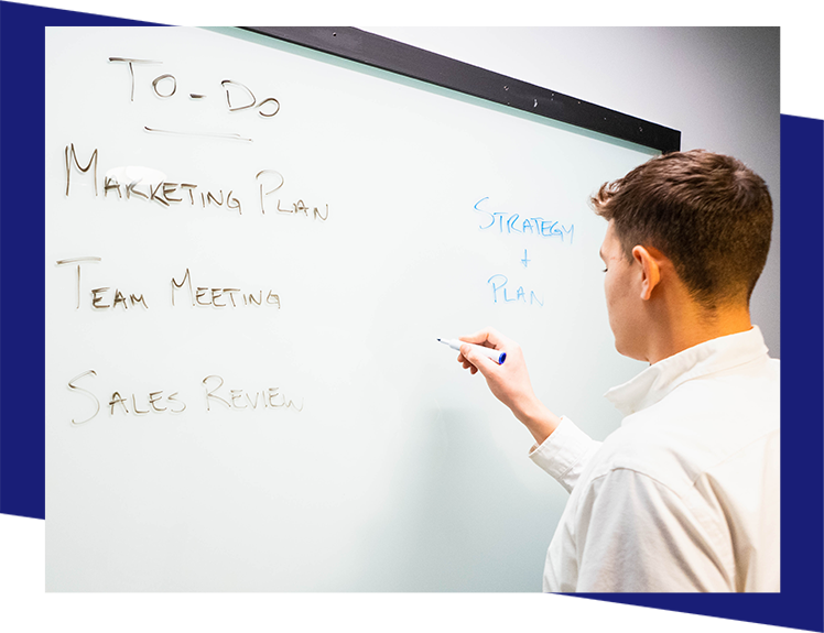 A man writing on the board with a marker.